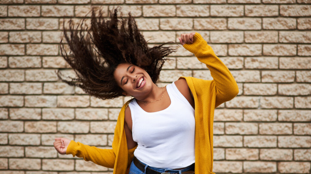 smile girl dancing with hair shake playful movement energy fun celebration fashion winner happy woman rhythm success freedom deal achievement brick wall background